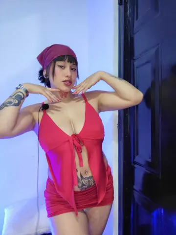 Young woman in a red bikini and headband posing in a moody blue-lit room.