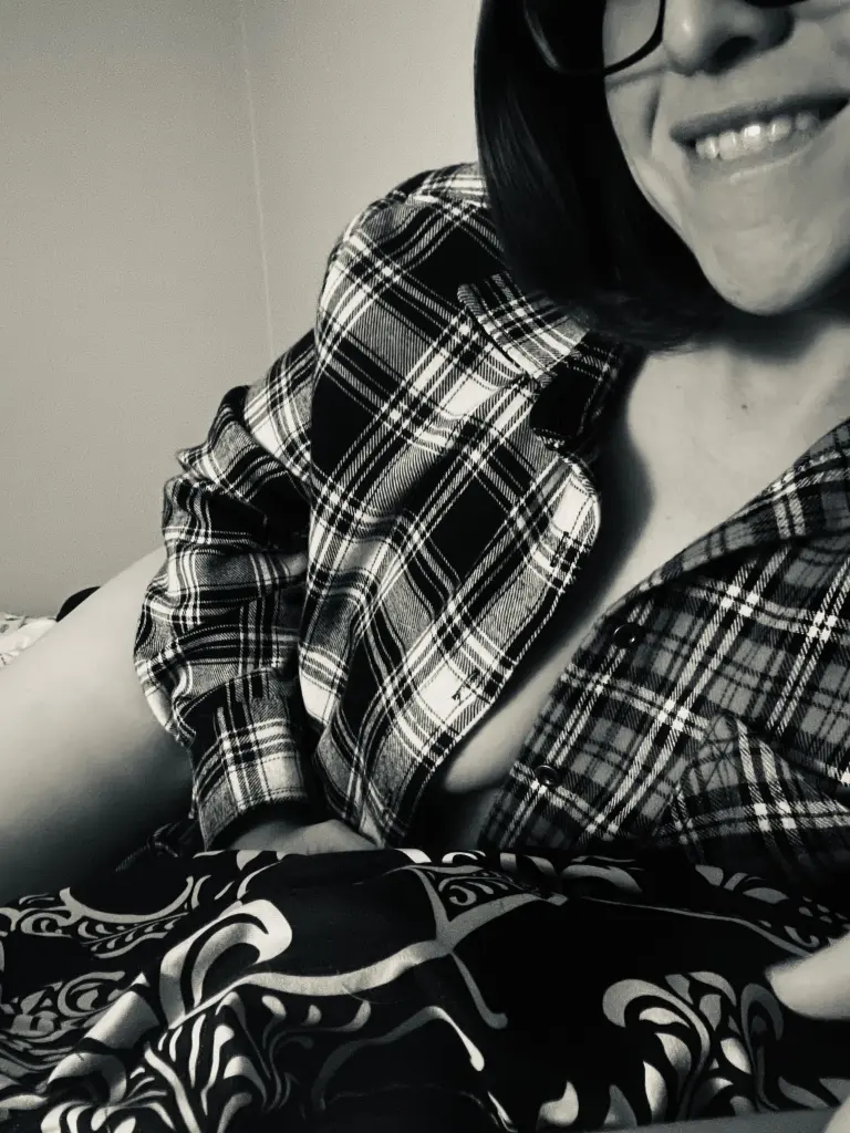 MartaShadow poses in a dark setting, showing her neck, shoulder, and a large black tattoo on her arm.