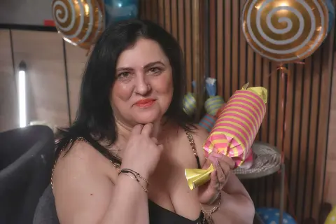 Smiling woman in a black top celebrating with colorful swirl balloons in a festive indoor setting.
