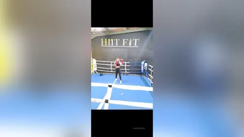 Athletic woman in black workout gear training in a professional boxing ring at a HIT FIT gym.