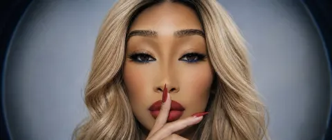 SOBLU — SOBLU poses with her finger to her lips, featuring long blonde hair and bold red lipstick.