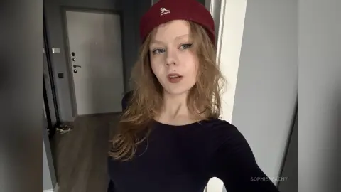 SophiePeachy wearing a dark long-sleeve shirt and a maroon baseball cap while looking into the camera.