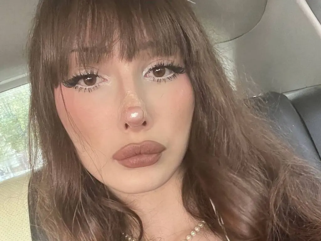 Close-up portrait of a young woman with brown bangs and soft makeup sitting in a car with a dreamy mood.