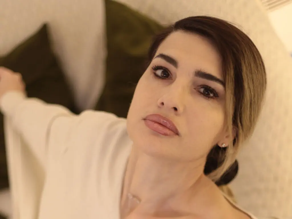 Close-up portrait of a woman in a white top relaxing on a couch with a soft, serene mood.