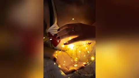 Woman in white lace holding glowing fairy lights in a warm, dreamy, and magical atmosphere.