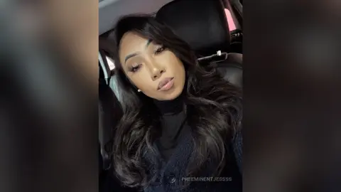 Young woman with long wavy hair wearing a black turtleneck sitting in a car with a moody aesthetic.
