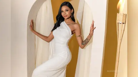 Elegant woman in a white evening gown posing in a warm, minimalist arched doorway setting.