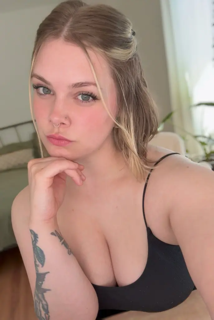 MissHarlow poses with a soft gaze, showing her blonde hair and bare shoulders in a close-up shot.