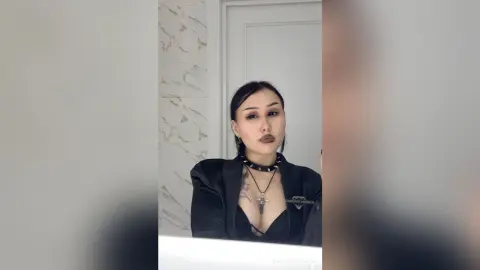 Moody portrait of a woman in a black outfit and choker necklace posing in a modern minimalist room.