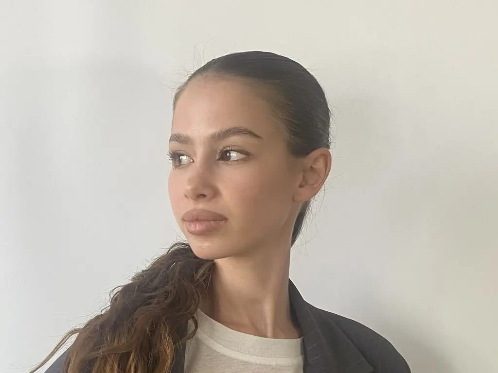 CarlynKernell poses with her long brown hair pulled back, wearing a dark blazer over a light top against a plain white wall.