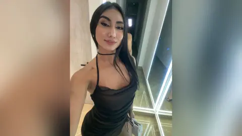 Smiling young woman in a black halter dress posing in a modern minimalist room.