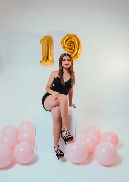 PaigeJaydeen poses outdoors with her long, dark braided hair, wearing a black tank top against a soft outdoor background.
