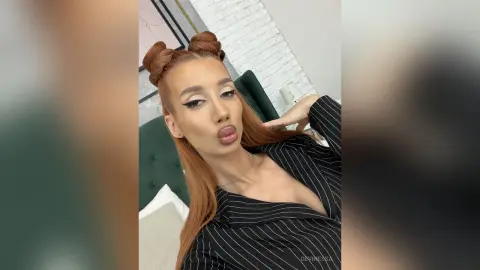 DeviNessa pouts her lips while wearing a black pinstriped shirt and a double bun hairstyle.