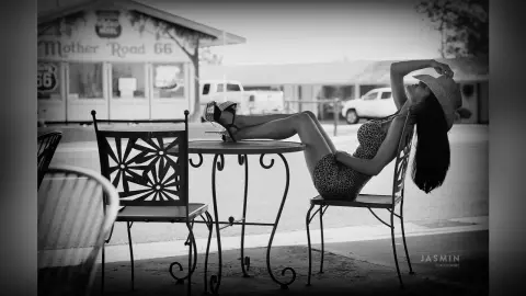 DrellaWolf — Stylish woman in leopard print dress relaxing at a vintage Mother Road 66 roadside cafe in black and white.
