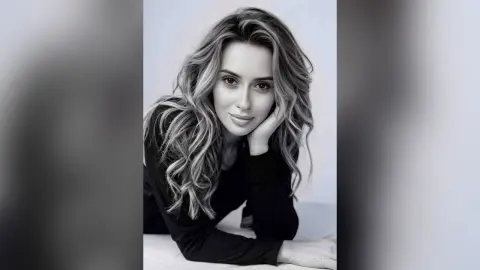Portrait of a smiling woman with wavy blonde hair wearing a black long-sleeve top in a soft, minimalist setting.