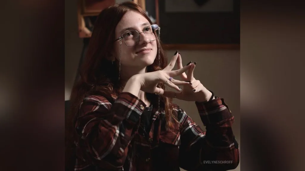Young woman with glasses and long hair in moody blue and red neon lighting.