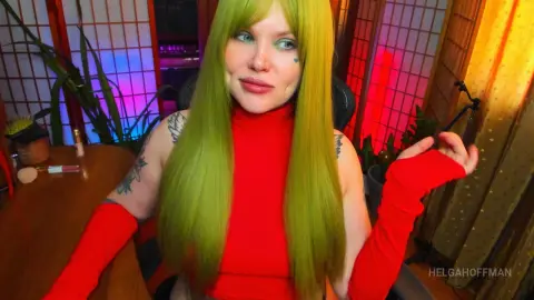 Woman with long lime green hair wearing a red turtleneck in a cozy room with warm lighting.
