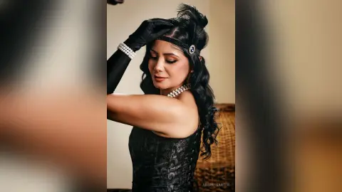 Elegant woman in black vintage lace dress and pearls posing with a glamorous 1920s Great Gatsby aesthetic.