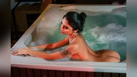 Young woman with dark hair relaxing in a bubbly hot tub at night for a serene spa experience.