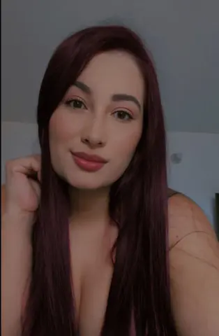 KiimberC poses close-up, showing her long dark hair and cleavage while looking directly at the camera.