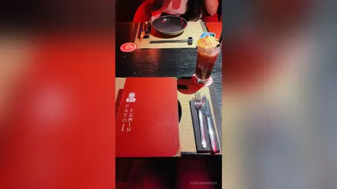 Red menu and iced cocktail on a dark restaurant table creating a moody dining atmosphere.