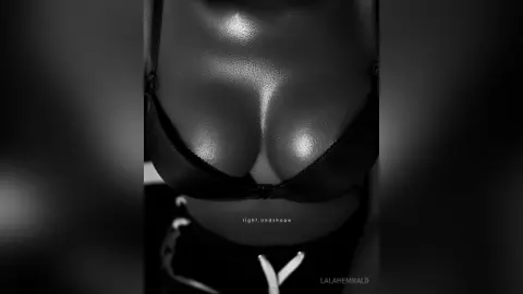 Close-up black and white artistic photography of a woman in a black bra highlighting skin texture and light.