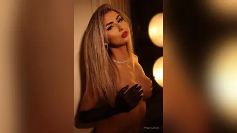 Glamorous woman in black evening gloves and red lipstick posing in moody, warm indoor lighting.