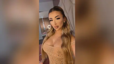Glamorous woman with long blonde hair wearing a sparkly beige sequin dress in a modern bedroom setting.