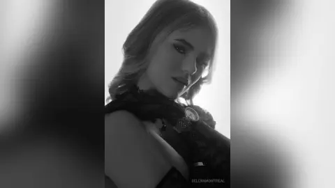 Moody black and white portrait of a blonde woman in a dark lace outfit against a bright background.