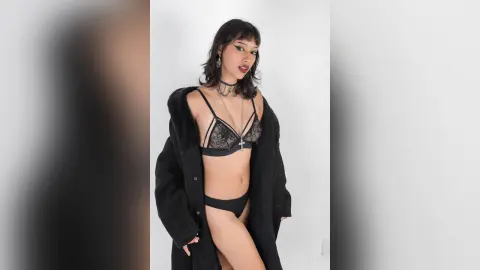LilithBrooks poses in black lace lingerie and an open black furry coat against a white background.