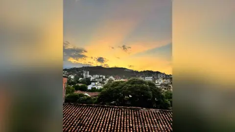 Scenic cityscape view of a town nestled under a golden sunset sky with rolling hills in the background.