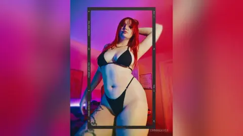 Red-haired woman in a black bikini posing in moody red lighting for a cinematic portrait.