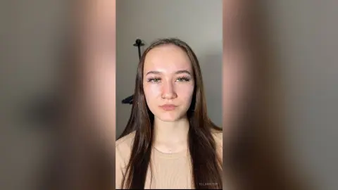 EllaVietor looks into the camera with long brown hair and a tan ribbed top against a plain wall.