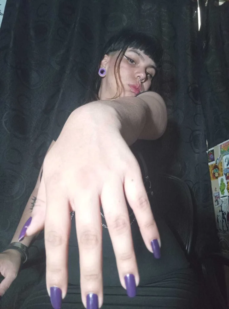 vanesabobs poses with her hand against her cheek, showing her face, dark hair, and a small nose piercing.