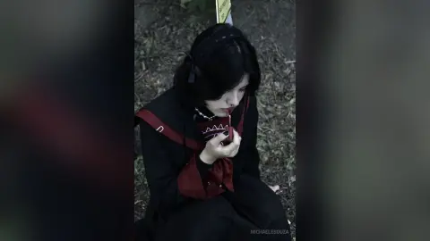 Melancholic young woman in dark gothic lolita outfit sitting in a forest setting.