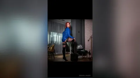 DonatellaRossy — DonatellaRossy poses in a blue shiny bodysuit and black thigh-high boots in a modern room.