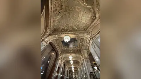 Ornate gold baroque ceiling with intricate carvings and crystal chandeliers in a luxurious vintage ballroom.