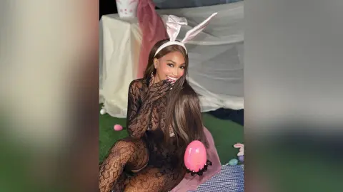 LiaTyler wears a black lace bodysuit and bunny ears while posing with a pink egg in a soft, indoor setting.