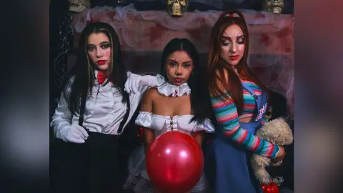 JessieLiu and two other women pose together, with JessieLiu wearing a white ruffled top and a red balloon held in front of her chest.