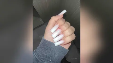 Close-up of long white coffin-shaped acrylic nails on a person wearing a grey ribbed sweater.