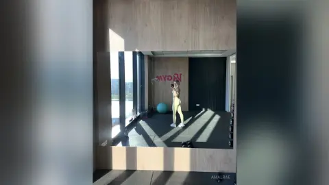 Fit woman in yellow gym set taking a mirror selfie in a bright, modern home workout room.