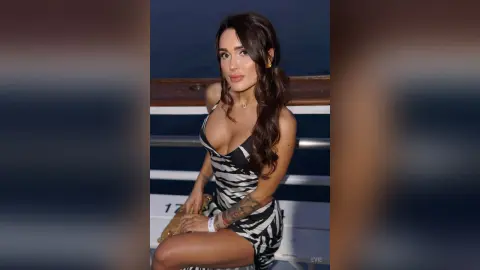Elegant woman in a black and white zebra print dress sitting on a boat at night.
