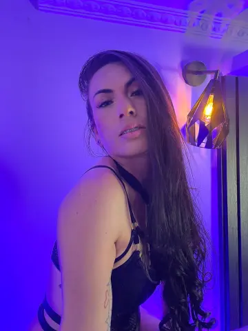 Young woman in black lingerie posing under moody purple neon lighting in a modern room.