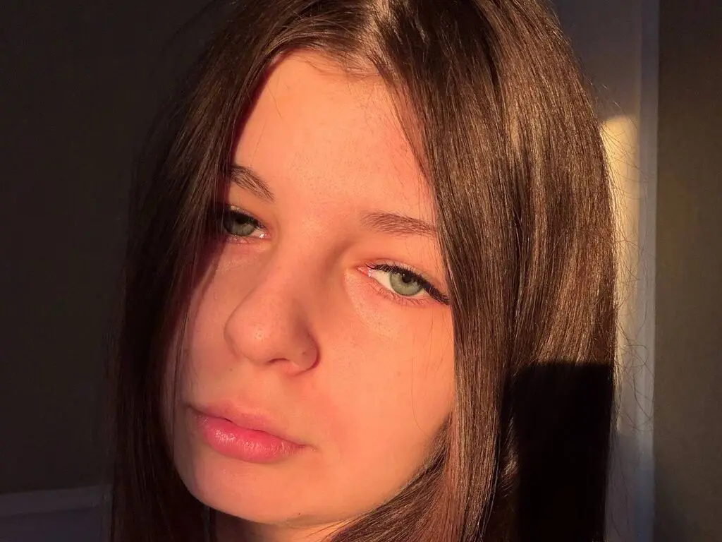 Close-up portrait of a young woman with long brown hair in warm, moody sunlight.