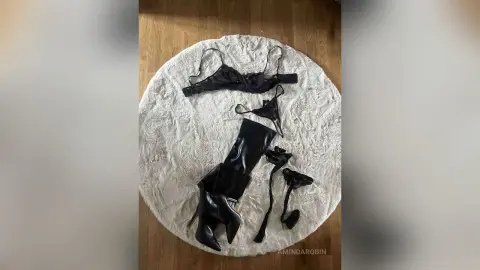 Elegant black lace lingerie set and high heel boots laid on a white faux fur rug.