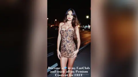 Elegant woman in a floral mini dress posing outdoors at night under city lights.