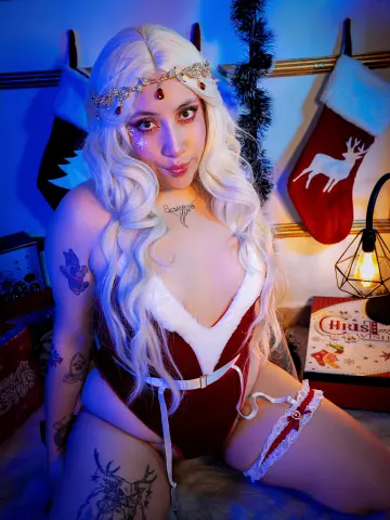 Blonde woman in red and white Christmas lingerie posing in a festive holiday setting with stockings.