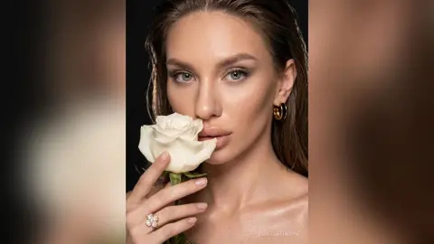 Beautiful woman with wet hair holding a white rose in a moody, elegant close-up portrait.