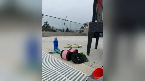 Personal belongings including a blue water bottle and sandals on a patio overlooking a misty coastal view.