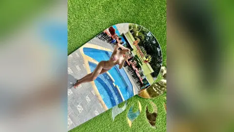 Woman in pink bikini relaxing on a poolside lounge chair at a sunny tropical resort.